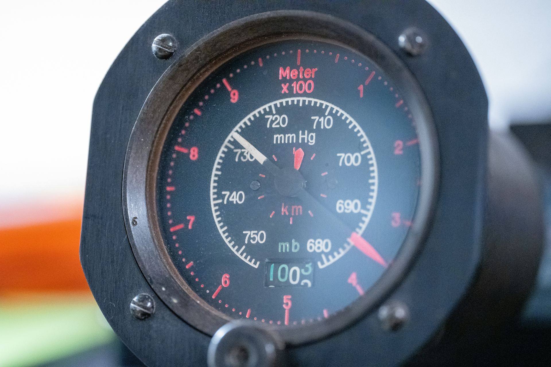 Vintage aircraft altimeter resting on a raw wooden workbench — needle mid-dial, glass slightly fogged