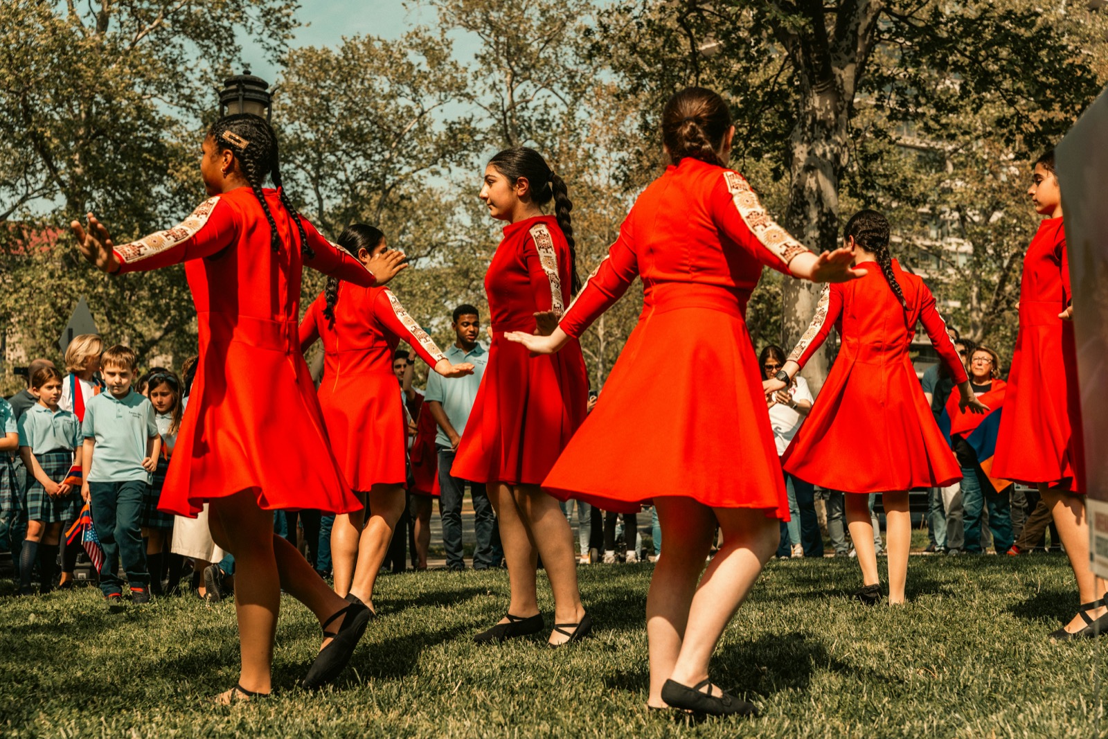 group of women in red dresses dancing in synchronized movement in an open field